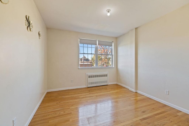 unfurnished room featuring radiator heating unit and light hardwood / wood-style flooring