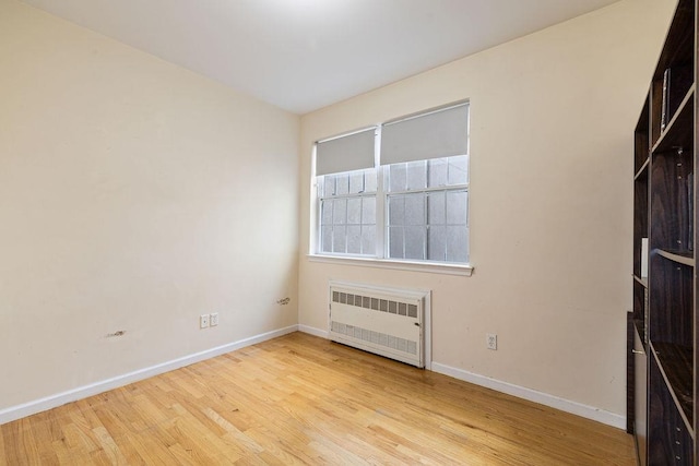 spare room with radiator heating unit and light wood-type flooring