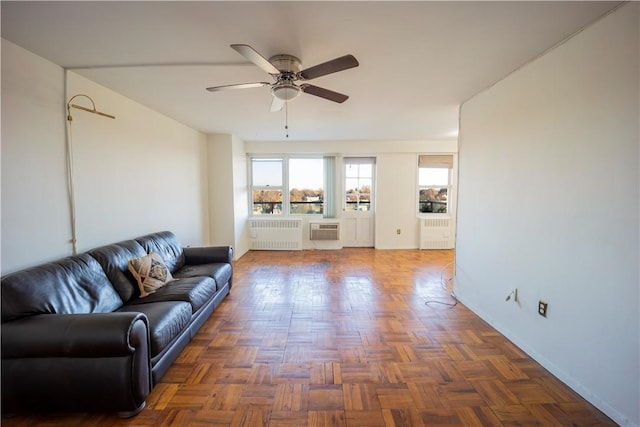 living room with dark parquet flooring, ceiling fan, radiator heating unit, and a wall mounted air conditioner