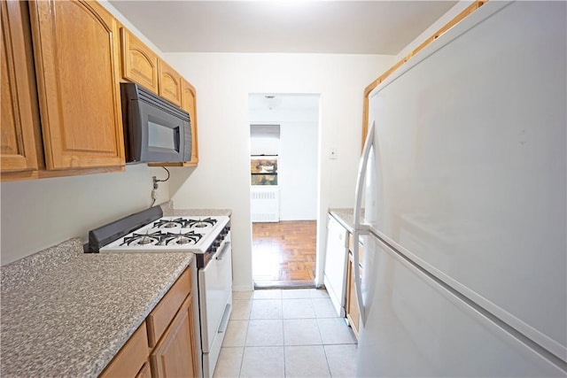 kitchen featuring light tile patterned floors, white appliances, and radiator