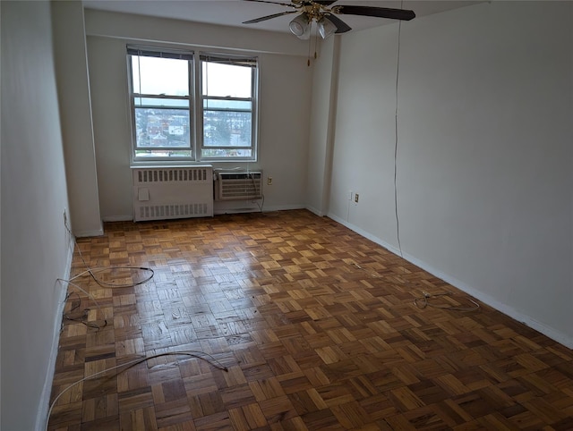 spare room featuring dark parquet flooring, a wall unit AC, radiator, and ceiling fan