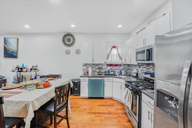 kitchen featuring white cabinets, appliances with stainless steel finishes, backsplash, and light hardwood / wood-style floors