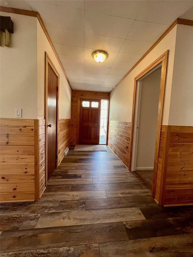 doorway to outside with dark hardwood / wood-style flooring and wood walls