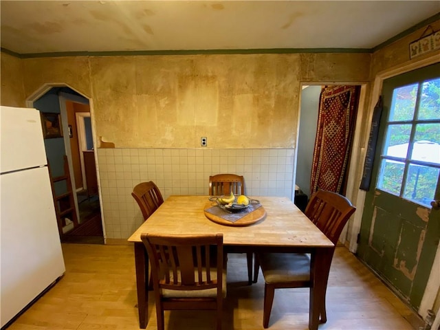 dining room featuring light hardwood / wood-style flooring, tile walls, and ornamental molding