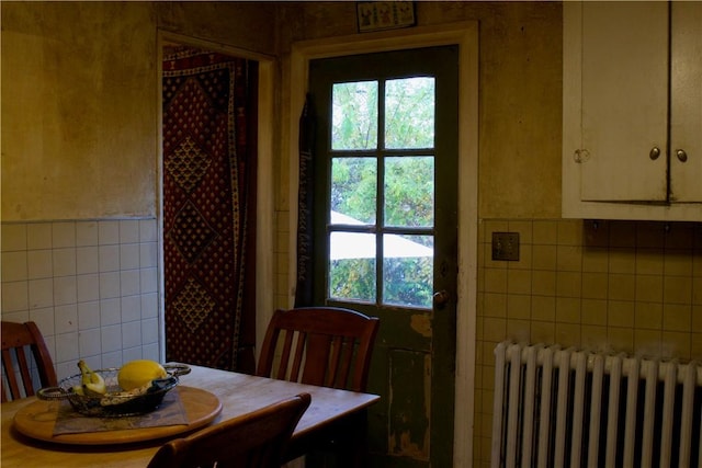 dining space featuring radiator and tile walls