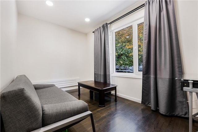 sitting room with dark hardwood / wood-style floors and a baseboard heating unit