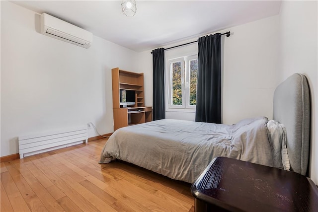 bedroom featuring a baseboard heating unit, a wall mounted air conditioner, and hardwood / wood-style flooring