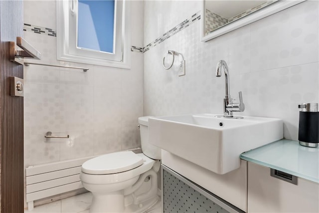 bathroom featuring sink, tile walls, and toilet