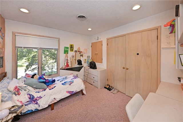 carpeted bedroom featuring a textured ceiling and a closet