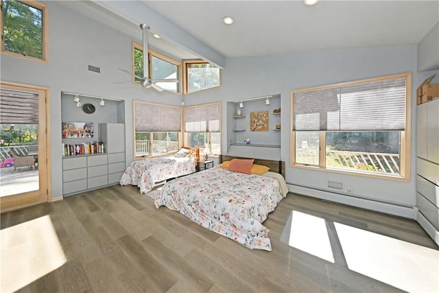 bedroom with a baseboard heating unit, dark wood-type flooring, high vaulted ceiling, and multiple windows