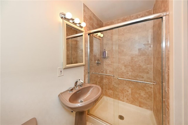 bathroom with a shower with door and sink