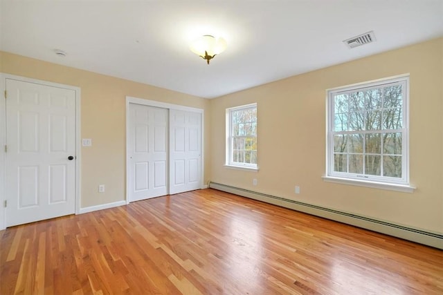 unfurnished bedroom with a baseboard radiator and light hardwood / wood-style flooring