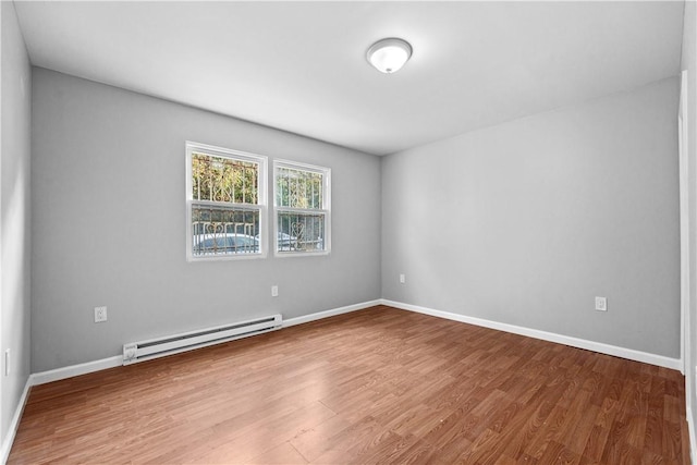 empty room featuring wood-type flooring and a baseboard radiator