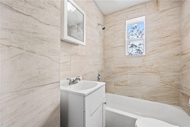 full bathroom featuring vanity, toilet, tile walls, and tiled shower / bath combo