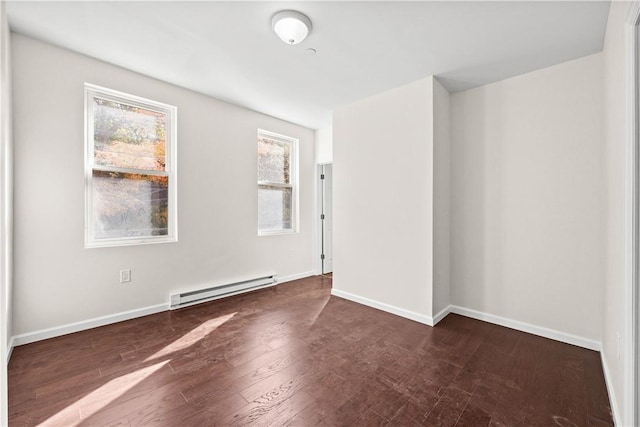 unfurnished room featuring baseboard heating and dark hardwood / wood-style flooring