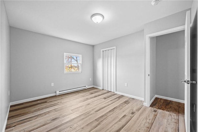 unfurnished bedroom with a closet, a baseboard radiator, and light wood-type flooring