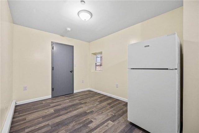 empty room featuring dark hardwood / wood-style floors and a baseboard heating unit