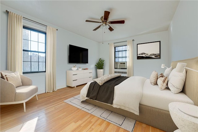 bedroom featuring hardwood / wood-style flooring, multiple windows, cooling unit, and ceiling fan