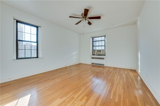 spare room featuring radiator heating unit, light hardwood / wood-style floors, a wealth of natural light, and ceiling fan