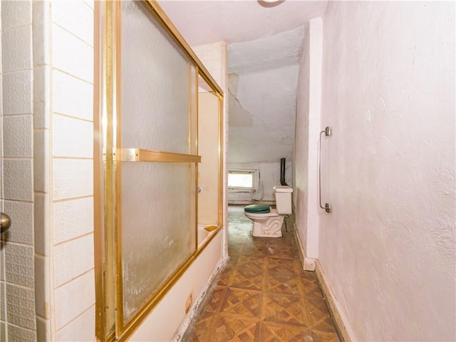 bathroom with shower / bath combination with glass door, toilet, and parquet floors