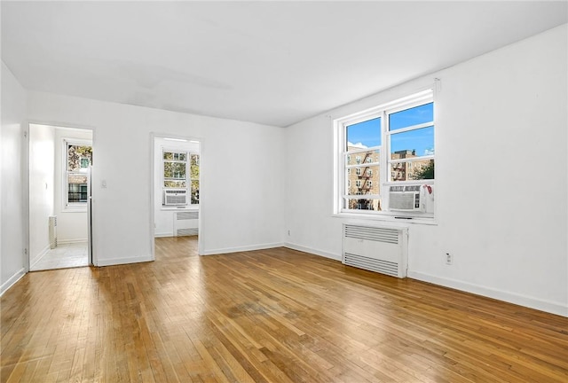 spare room featuring light hardwood / wood-style floors, radiator, and cooling unit