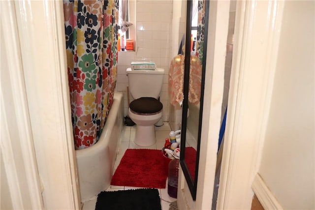 bathroom with tile patterned flooring, shower / bath combo, toilet, and tile walls