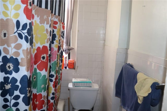 bathroom featuring curtained shower, tile walls, and toilet