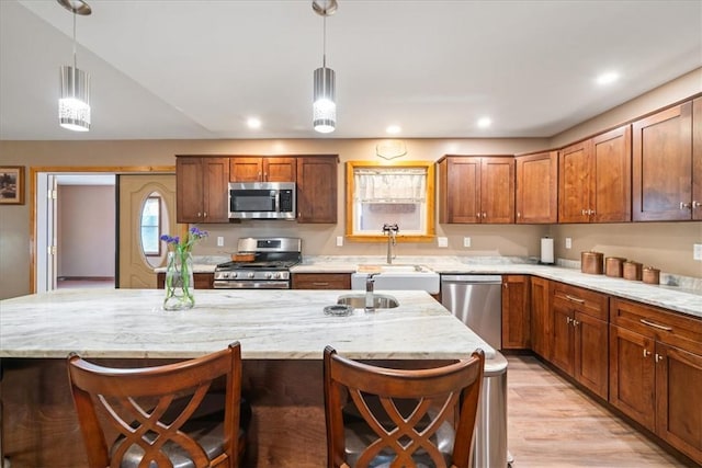 kitchen with a breakfast bar, light wood-type flooring, stainless steel appliances, and a sink