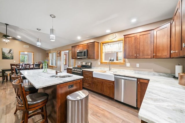 kitchen with vaulted ceiling, a breakfast bar area, stainless steel appliances, and a sink