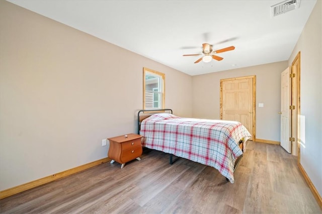 bedroom featuring light wood-type flooring, baseboards, visible vents, and a ceiling fan