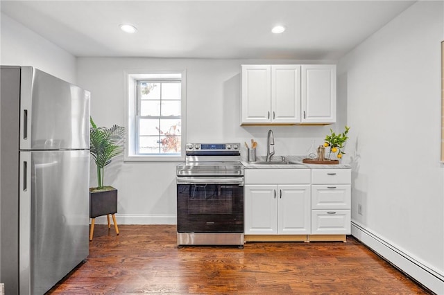 kitchen with sink, dark wood-type flooring, a baseboard radiator, white cabinets, and appliances with stainless steel finishes