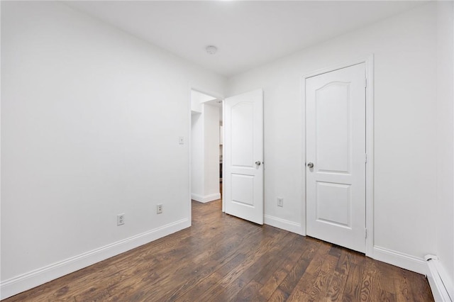 unfurnished bedroom with dark hardwood / wood-style floors and a baseboard radiator