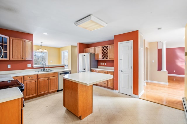 kitchen featuring a center island, sink, decorative light fixtures, stainless steel appliances, and decorative columns