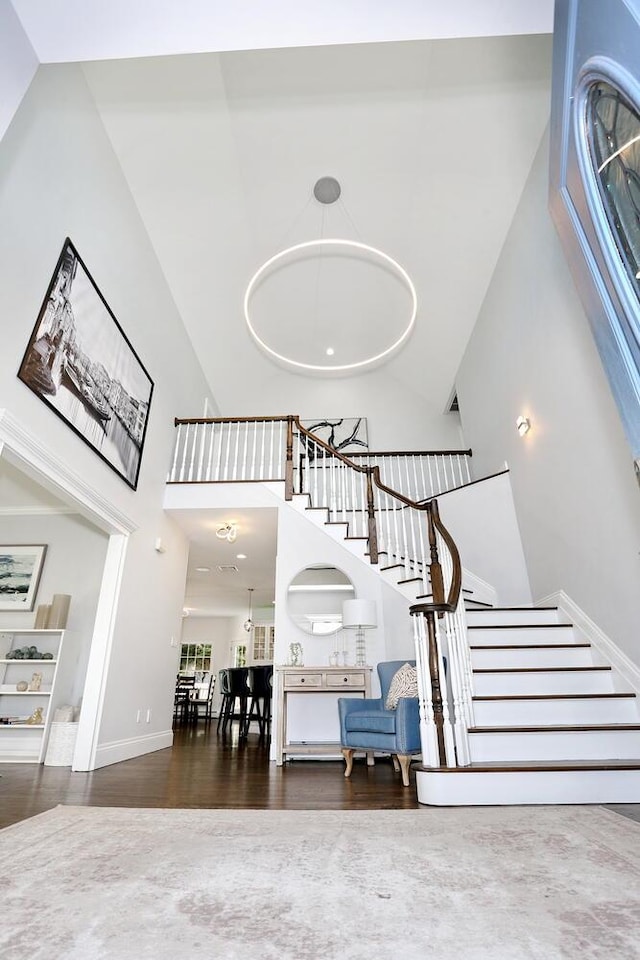 stairway with hardwood / wood-style flooring and a towering ceiling