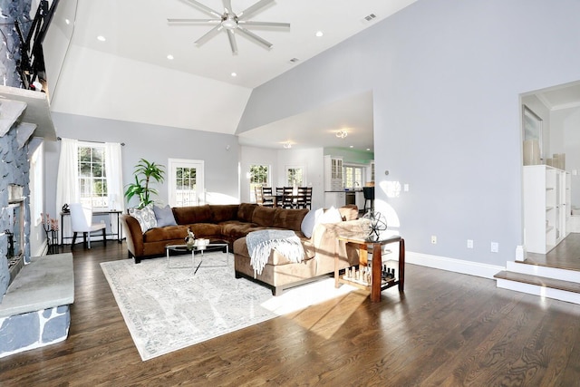 living room featuring high vaulted ceiling, dark hardwood / wood-style flooring, and a stone fireplace