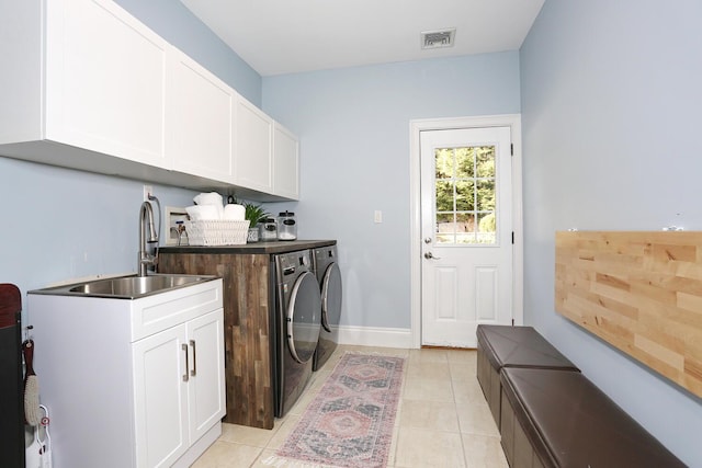 laundry room featuring cabinets, light tile patterned floors, sink, and independent washer and dryer