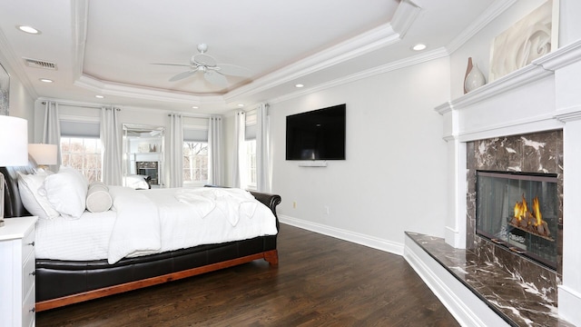 bedroom featuring a premium fireplace, ceiling fan, a raised ceiling, and crown molding