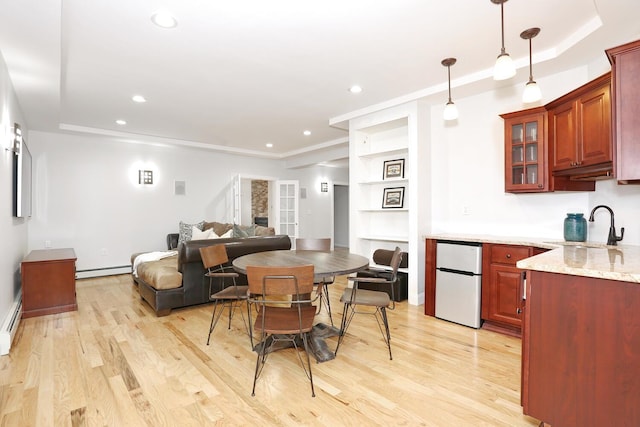 kitchen featuring refrigerator, light hardwood / wood-style floors, hanging light fixtures, baseboard heating, and sink