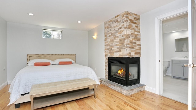 bedroom featuring sink, ensuite bathroom, hardwood / wood-style floors, and a fireplace