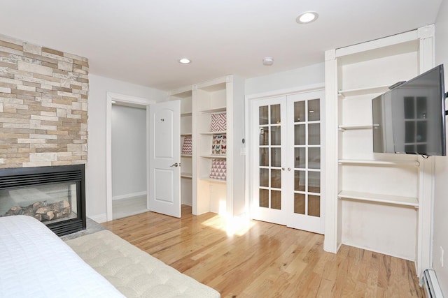 bedroom with light wood-type flooring, french doors, and a baseboard heating unit