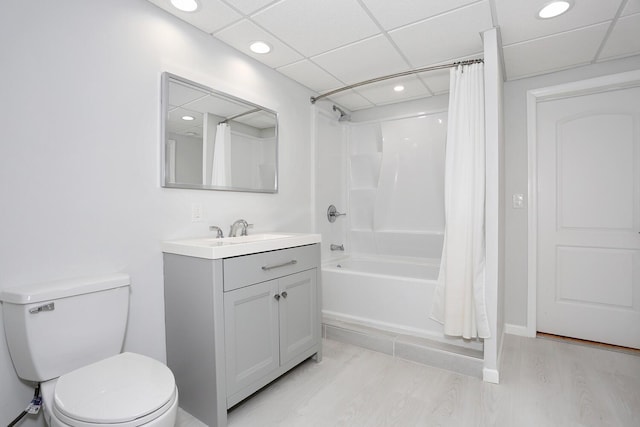 full bathroom with shower / tub combo, a paneled ceiling, hardwood / wood-style floors, toilet, and vanity