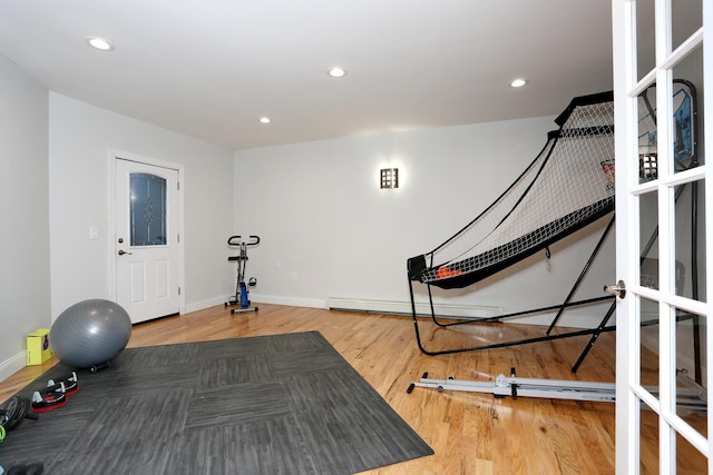 workout area featuring hardwood / wood-style floors and a baseboard heating unit