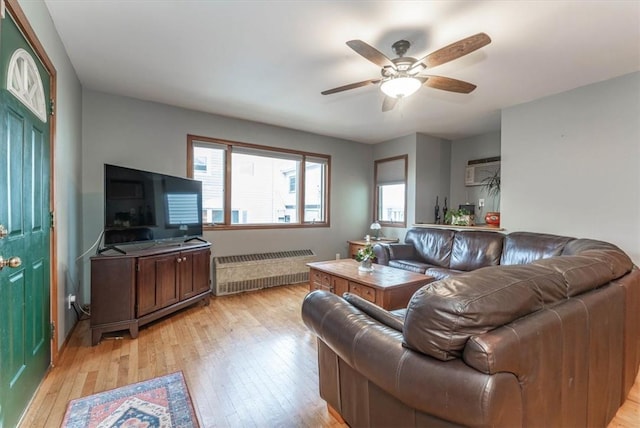 living room featuring ceiling fan, radiator heating unit, and light hardwood / wood-style flooring