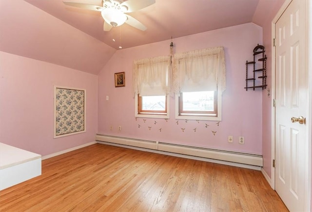 spare room featuring ceiling fan, vaulted ceiling, wood-type flooring, and a baseboard heating unit