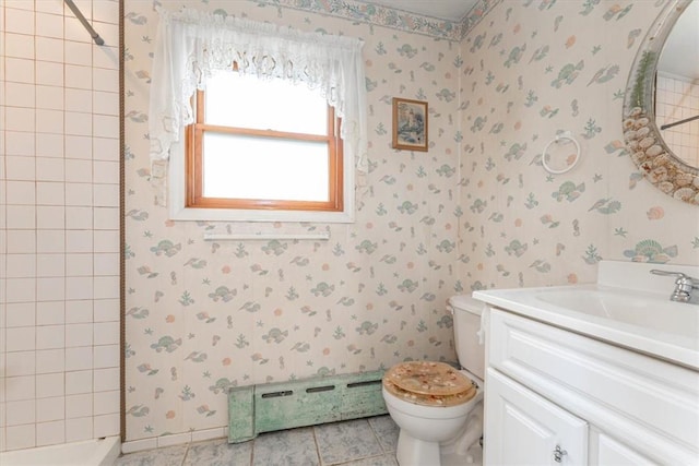 bathroom featuring tile patterned flooring, a baseboard heating unit, tiled shower, toilet, and vanity