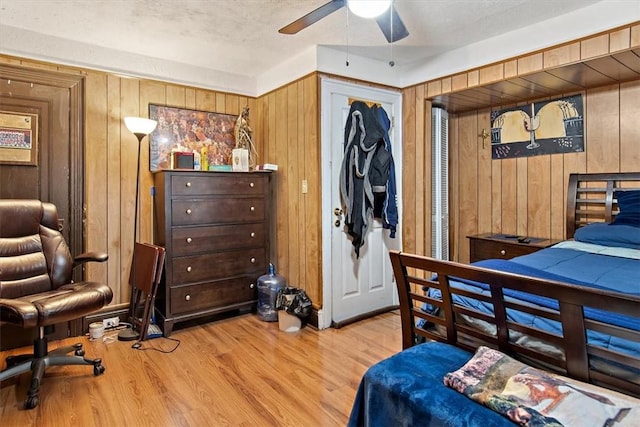 bedroom with wood-type flooring, a closet, ceiling fan, and wood walls