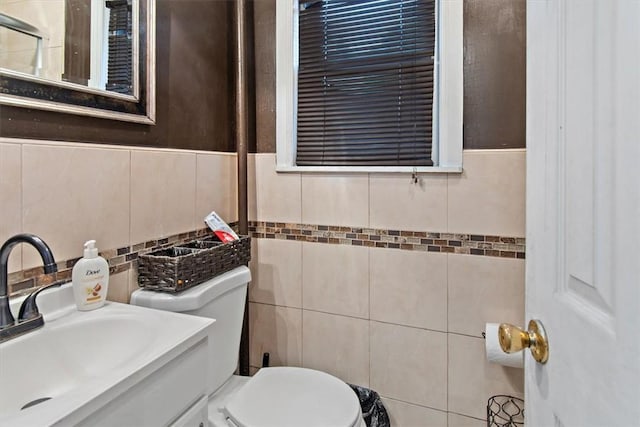 bathroom featuring vanity, toilet, and tile walls