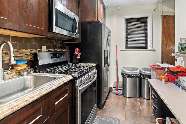 kitchen with dark brown cabinetry, sink, light tile patterned flooring, and appliances with stainless steel finishes