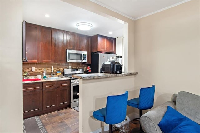 kitchen with sink, tasteful backsplash, crown molding, a breakfast bar area, and appliances with stainless steel finishes