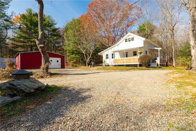 view of front of house featuring covered porch, a garage, and an outbuilding